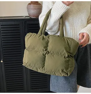 Detailed close-up of olive green quilted puffer tote bag with soft padded handle texture