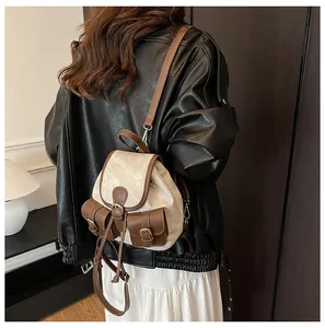 Gros plan d'un mini sac à dos vintage en toile crème avec détails en similicuir marron