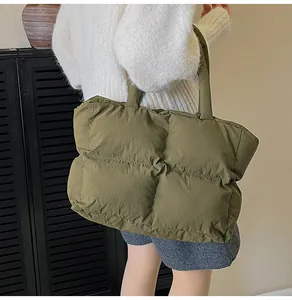 Close-up of olive green quilted puffer tote bag with wide shoulder strap on model