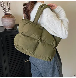 Olive green quilted puffer tote bag with wide shoulder strap shown on person in modern interior