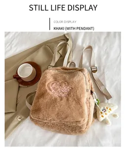 Flat lay of khaki plush backpack with pink heart embroidery and cloud pendant