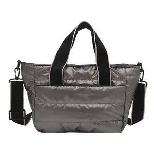 Schicke metallisch-silberne Stepp-Tote-Bag mit schwarzen Riemen auf weißem Hintergrund