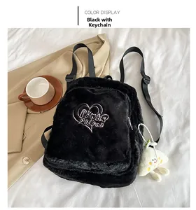 Détail d'un sac à dos noir en peluche avec broderie cœur rose et charm nuage