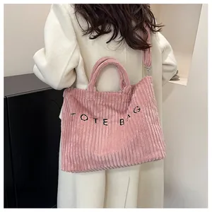Gros plan du sac cabas en velours côtelé rose avec broderie et bandoulière longue