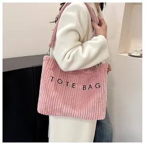 Détail du sac cabas en velours côtelé rose avec texte brodé noir et tissu texturé
