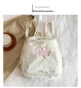 Détail d'un sac à dos en peluche blanche avec broderie cœur rose et poche zippée