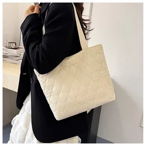 Detail of off-white quilted tote bag with wavy texture and wide shoulder straps