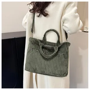 Détail d'un sac cabas en velours côtelé vert foncé avec texture nervurée et broderie