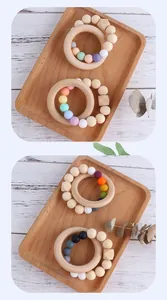 Makroaufnahme von Silikonperlen in Macaron-Farben und Baby-Beißring aus Naturholz