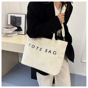 Détail du sac cabas en velours côtelé blanc avec broderie noire sur tenue chic