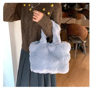 Detail of soft faux fur texture on a light blue plush tote bag held by a model