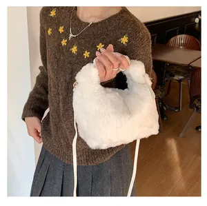 Detail of soft white plush handbag with gold hardware and slim leather crossbody strap