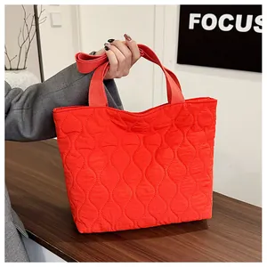 Close-up of bright red quilted tote bag with wavy stitching and fabric handles