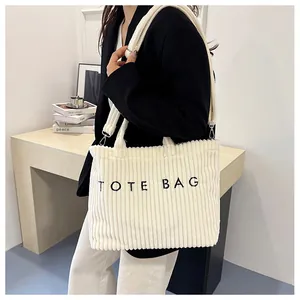 Détail du sac cabas en velours côtelé blanc avec texture, texte et bandoulière amovible