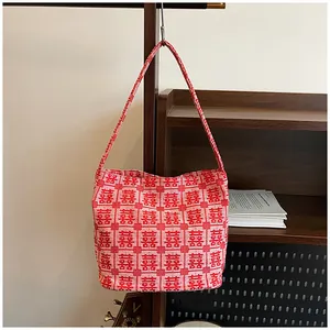 Detailed view of red knitted tote bag featuring white traditional Xi character patterns