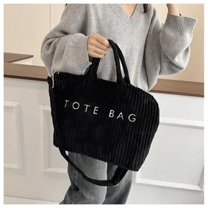 Détail du grand cabas en velours côtelé noir avec inscription TOTE BAG et bandoulière