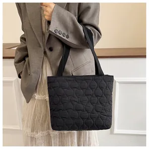 Close-up of black quilted tote bag with wavy stitching and fabric straps for daily use