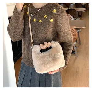 Detail der flauschigen cremeweißen Handtasche mit Faltenkapitel und Leder-Schultergurt