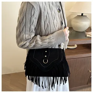 Detail of bohemian black suede crossbody bag with long fringes and golden D-ring buckle