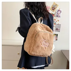 Dettaglio zaino di peluche kaki con ricamo a cuore rosa e ciondolo a forma di orsetto