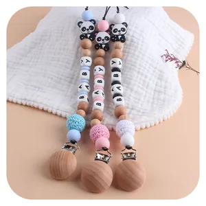 Three handmade beech wood baby pacifier clips with panda beads in blue, pink, and white