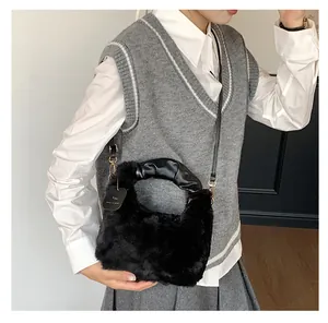 Detail der Plüschhandtasche in Schwarz mit PU-Ledergriff und modischem Anhänger
