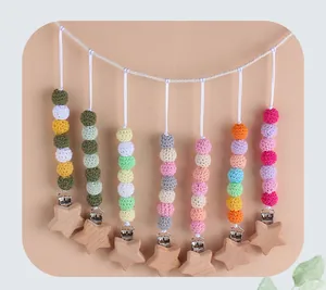 Detail of handcrafted crochet baby pacifier clips with beech wood star and colorful yarn balls