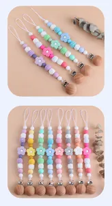 Detail of baby pacifier clips with beech wood, silicone beads and floral accessories