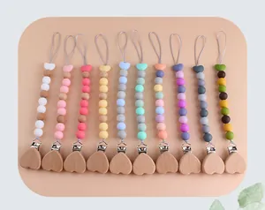 Flat lay of colorful beech wood and silicone heart pacifier clips in various colorways