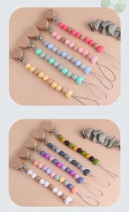 Detail of wooden heart pacifier clip with colorful silicone beads on warm background