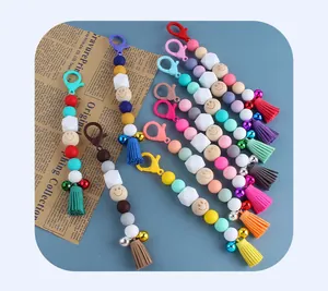Flat lay of colorful beaded lobster clasp keychains with tassels and bells on blue surface