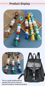 Close-up of DIY silicone bead keychain with smiley face wood bead, bell and leather tassel