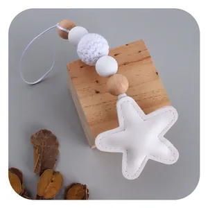 Star-shaped faux leather pendant with crochet ball and wooden beads on grey background