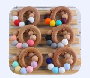 Macro detail of macaron silicone beads and beech wood teething rings on a wooden tray