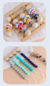 Detail of wooden baby rattle teether and silicone pacifier clip set in Morandi tones
