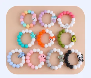 Variety of silicone baby teething bracelets with cartoon animal pendants on beige background