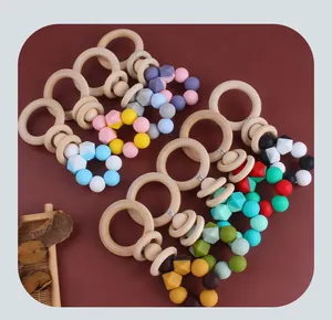 Detail of baby wooden teething ring with colorful food-grade silicone beads on red background