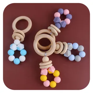 DIY baby teether set with natural wooden rings and colorful silicone beads on dark background