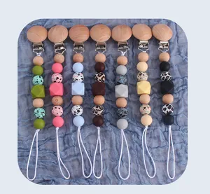 Detail of seven baby pacifier clips featuring leopard silicone beads and natural beech wood