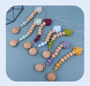 Detail view of colorful silicone pacifier clips with beech wood and leaf pendants