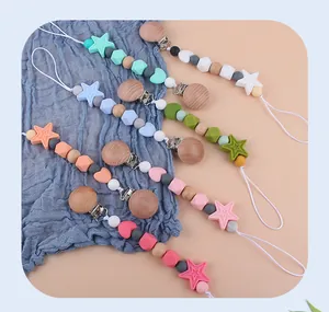 Detailed close-up of silicone star and wooden bead pacifier clips in five diverse colors
