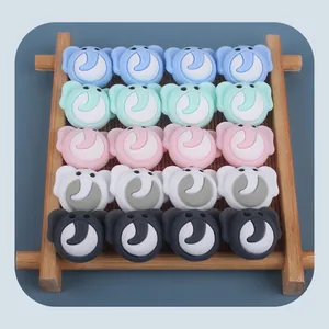 Detailed view of 20 silicone elephant teether beads in five colors on a bamboo tray