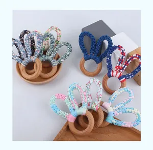 Macro shot of handcrafted beech wood baby teething rings with colorful woven rabbit ears