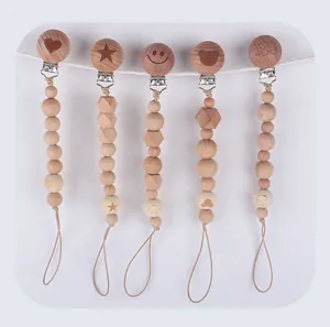 Detail of five wooden pacifier clips with heart, star, and animal engravings