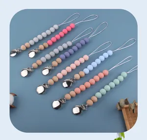 Detailed view of silicone and wooden baby pacifier clips in various pastel colors