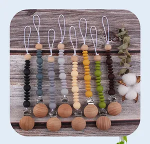 Silicone and beech wood pacifier clips in 8 Morandi colors on natural wood background