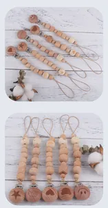 Detail of natural beech wood pacifier clip with animal engravings and geometric beads