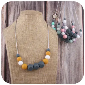 Silicone teething necklace for babies with yellow and grey hexagon beads on model