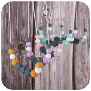 Multi-color silicone baby teething necklace with geometric beads on a wooden background