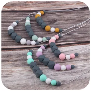 Silicone teething necklaces with round and geometric beads in pastel colors on dark wood
